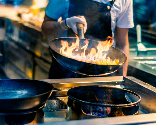 Chef Using a Wok in a Kitchen With Flames in the Pan Chef Using a Wok in a Kitchen With Flames in the Pan